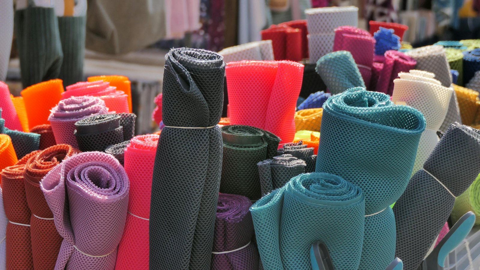 Vibrant rolls of mesh fabric displayed at a market in Mayen, Germany.